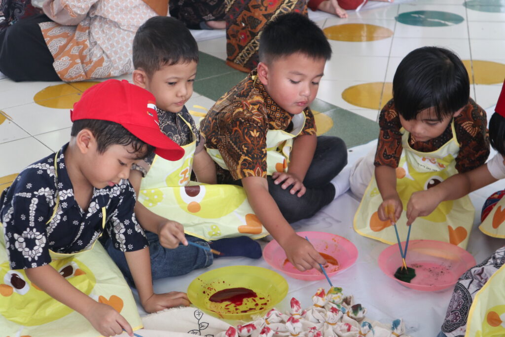 Empat murid laki-laki TK Islam Al Azhar 12 Cikarang sedang fokus melakukan aktivitas anak prasekolah mewarnai kain.