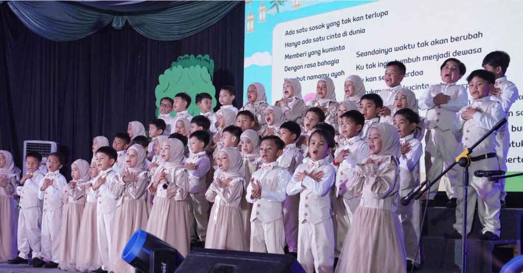 Paduan suara murid bernyanyi penuh penghayatan dengan tangan di dada pada acara perpisahan TK.