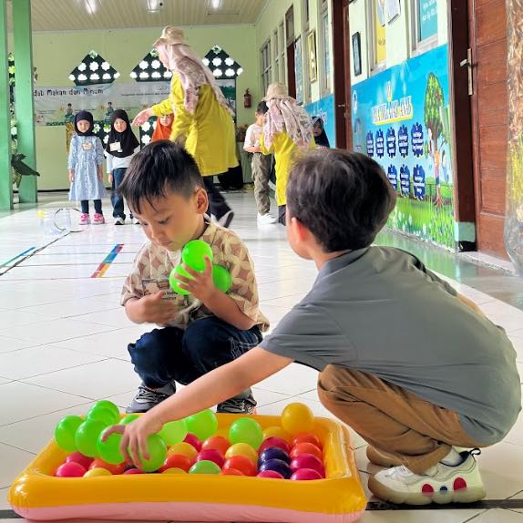 Murid TKIA 12 Cikarang sedang memegang bola.