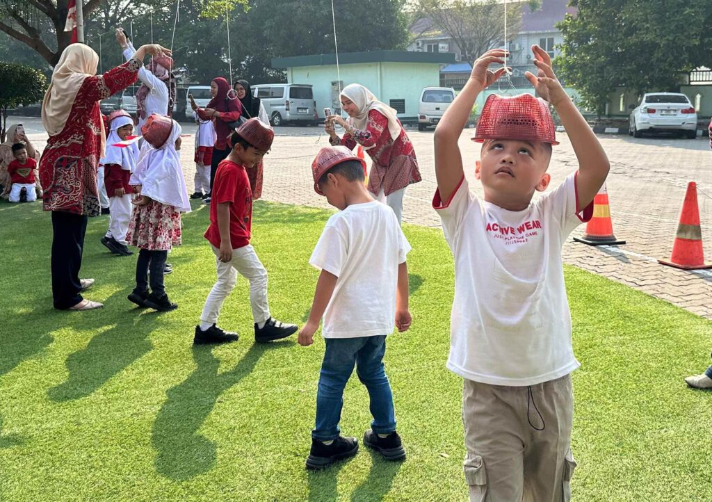 Murid TK Islam Al Azhar 12 Cikarang mengikuti permainan tali secara berkelompok di lapangan.